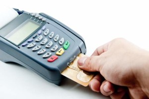 Hand holding credit card inserted into CC terminal